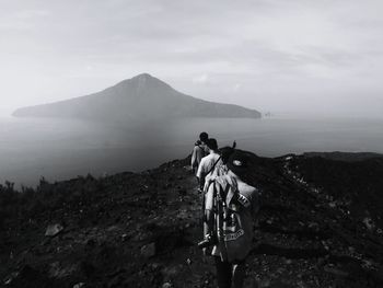 People riding bicycle on mountain against sky