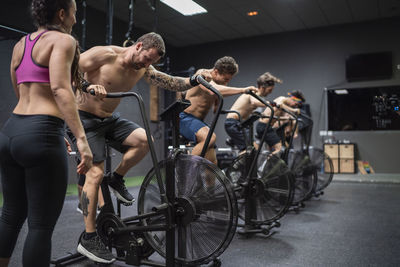 Athletes sitting on bike while exercising at gym