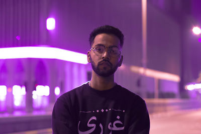 Portrait of young man standing on road at night