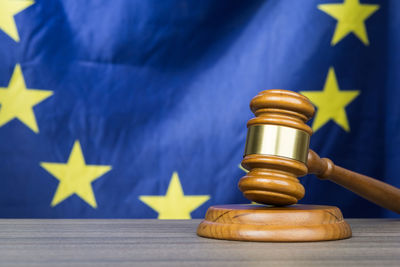 Close-up of gavel and hammer on table against national flag