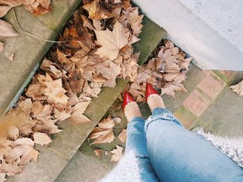 Low section of man standing on fallen leaves