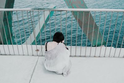 Rear view of woman on railing against sea
