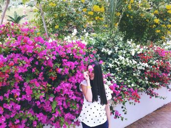 Young woman standing by flowering plants at park