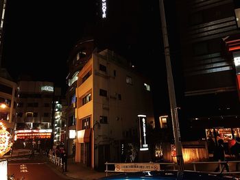 Illuminated street amidst buildings in city at night