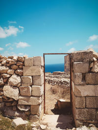 Stone wall by sea against sky