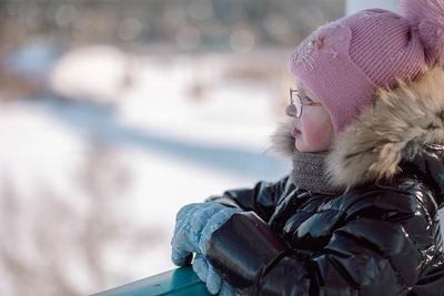 Little girl walks outdoors on winter snowy day in park