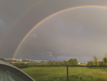 Scenic view of rainbow over field against sky