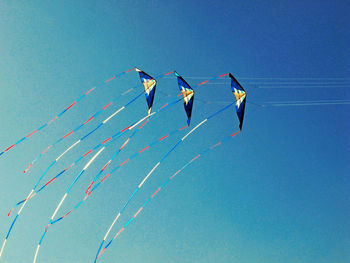 Low angle view of umbrellas against clear blue sky