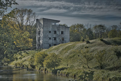 Scenic view of lake by trees and buildings against sky