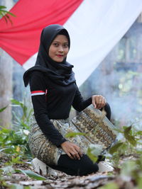 Portrait of young woman standing against plants