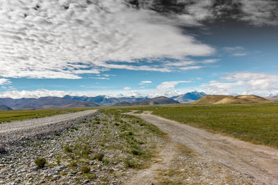 Scenic view of road by mountains against sky