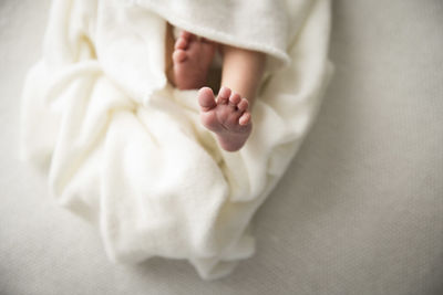 Close up of detail, newborn baby foot, swaddled in white blanket