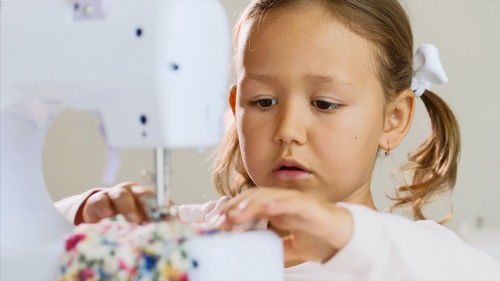 Close-up of cute girl sewing textile at home