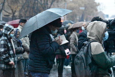 People standing on wet street in rain