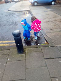 Rear view of men holding umbrella on street