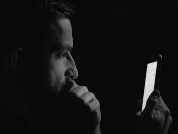 Close-up of man using smart phone in darkroom