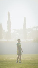 Rear view of woman walking on field against sky