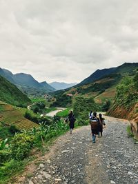 Rear view of people walking on mountain against sky