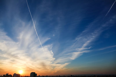 Low angle view of vapor trail in sky during sunset