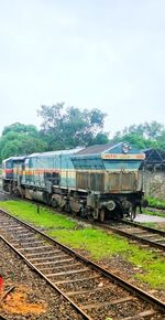 Train by railroad tracks against sky
