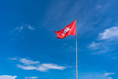 Historic flag of lithuania, rider with sword on white horse on red background flutters on blue sky