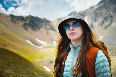 Portrait of young woman standing against mountain