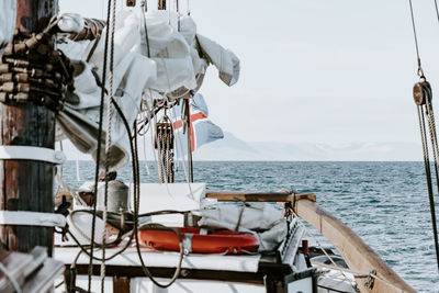 Sailing ship moving on sea by mountains against sky