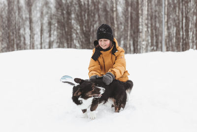 A girl plays with a corgi dog in a winter park