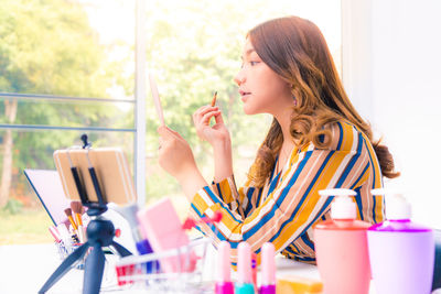 Side view of young woman sitting on table