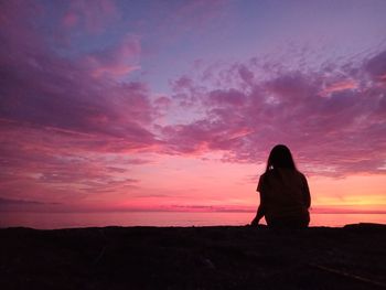 Silhouette woman standing on landscape against sky during sunset