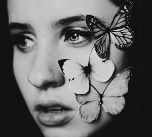 Close-up of young woman holding leaf over black background