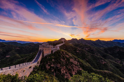 Scenic view of mountain against cloudy sky during sunset