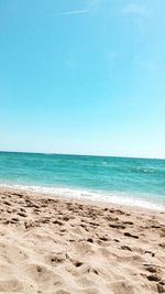 Scenic view of beach against clear blue sky