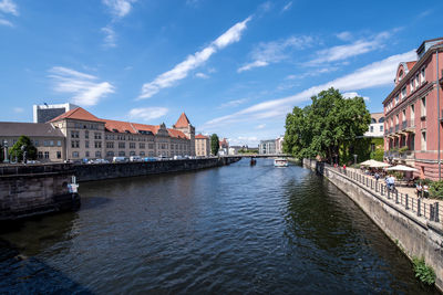 Buildings by river against sky