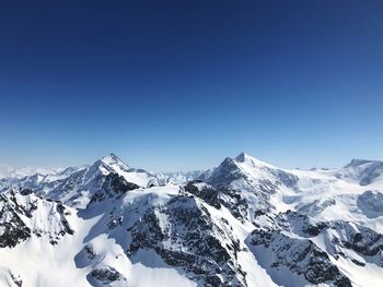 Scenic view of snowcapped mountains against clear blue sky