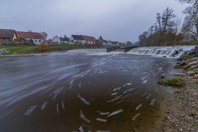 Scenic view of river by buildings against sky