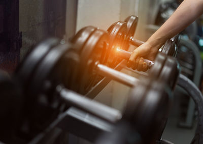 Cropped hand of woman holding dumbbell in gym