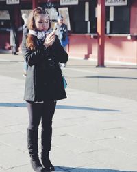 Young woman holding incense on walkway during sunny day