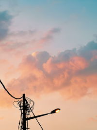 Low angle view of silhouette electricity pylon against sky during sunset