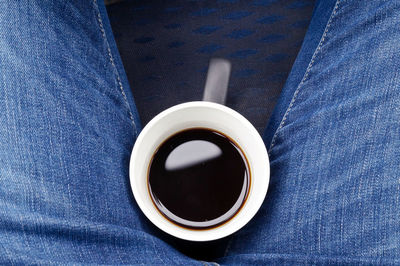 Directly above shot of person with coffee cup between legs