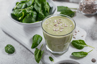 Glass of homemade healthy green smoothie with fresh baby spinach