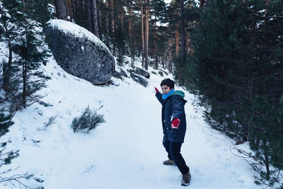 Full length of boy playing with snow in forest