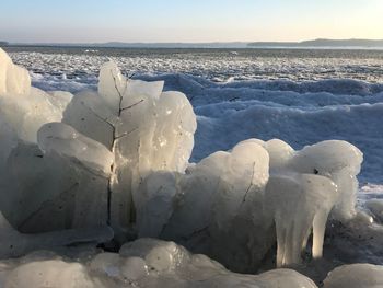 Close-up of snow on sea shore against sky