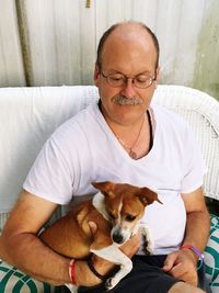 Man with dog sitting on sofa at home