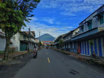 Road by buildings in city against sky