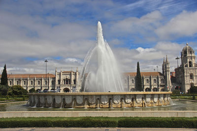 Fountain in city against sky