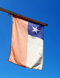 Low angle view of flag against clear blue sky