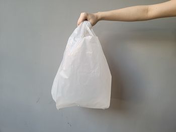 Midsection of person holding paper against white background