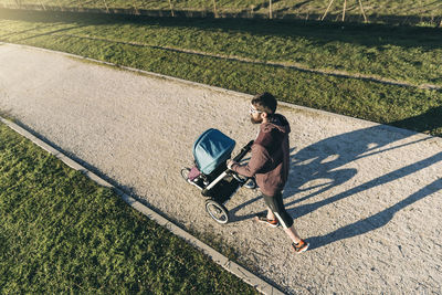 High angle view of man walking with baby stroller on road