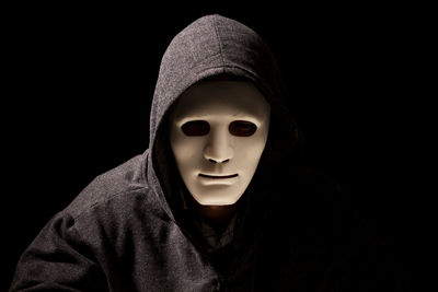 Portrait of criminal in mask against black background
